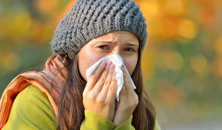 Tjej med förkylning eller allergi snyter sig